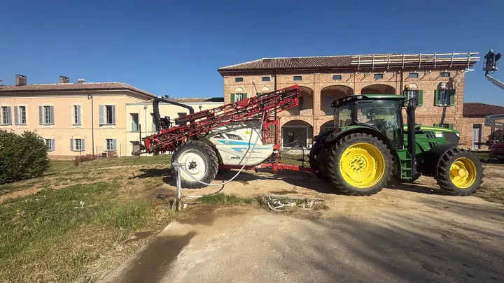 Trattore con grande atomizzatore davanti a una villa