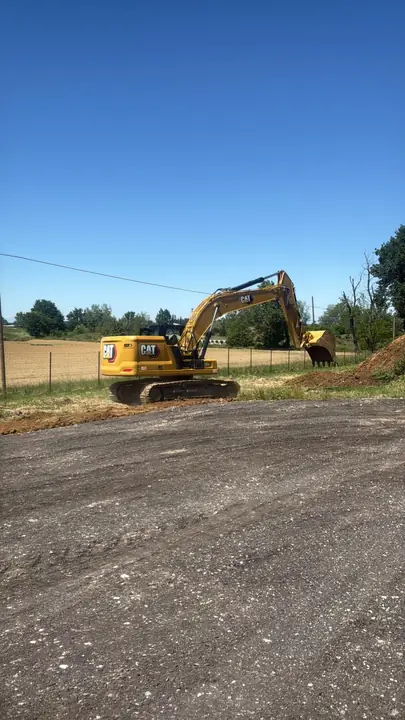 Escavatore cingolato al lavoro vicino a una strada sterrata